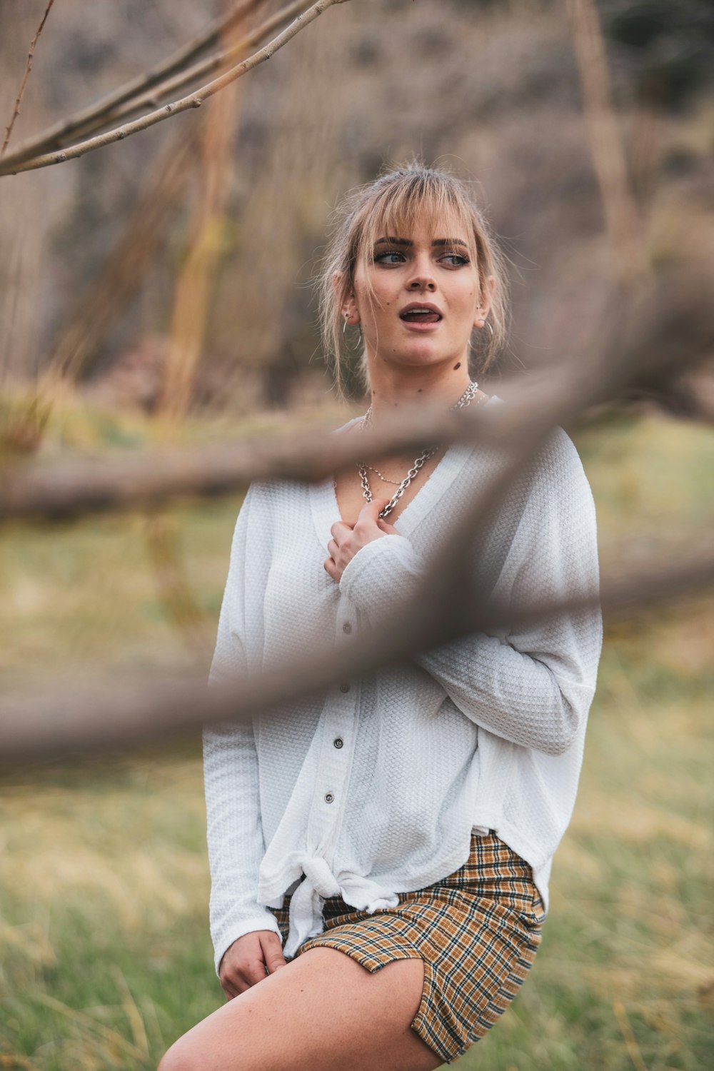 woman in white long sleeve shirt holding brown wooden fence during daytime