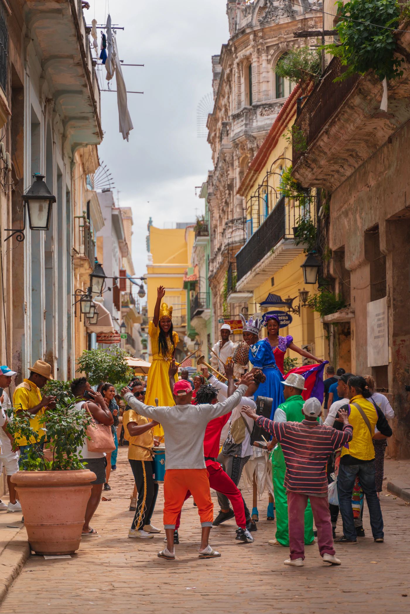 People in colourful traditional Cuban dress standing on the steps of an ornate colonial building in Havana Cuba with vivid red and yellow costumes against the weathered pale facade