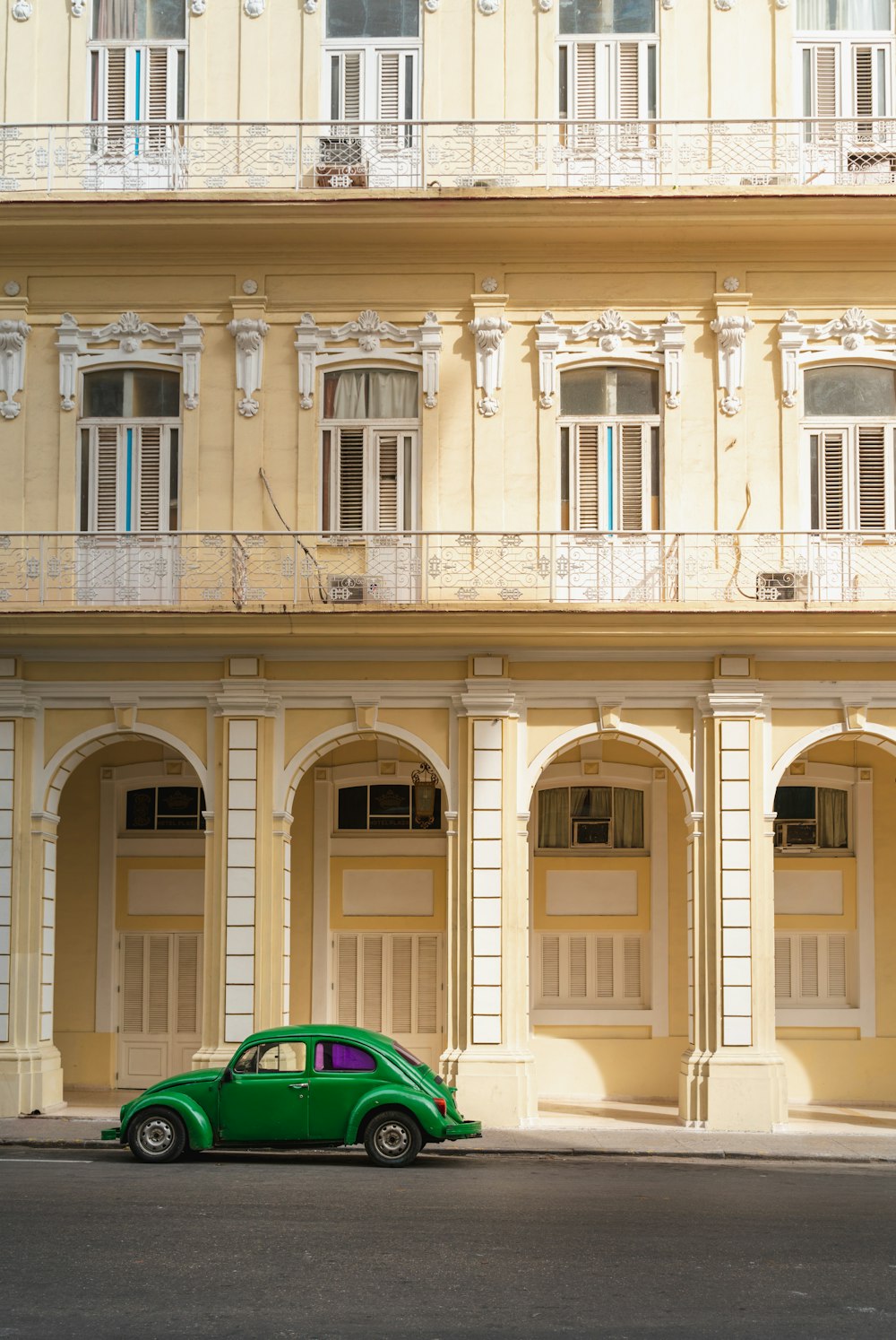 carro verde e azul estacionado ao lado do edifício de concreto bege