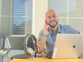 A friendly business representative smiling while using a laptop surrounded by drone and technology icons.
