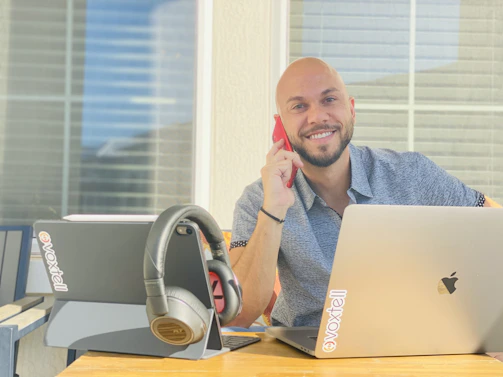 A friendly business representative smiling while using a laptop surrounded by drone and technology icons.