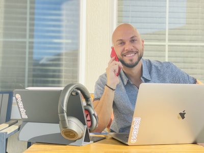 An Albanian business owner smiling while using AI-powered software on a desktop computer.