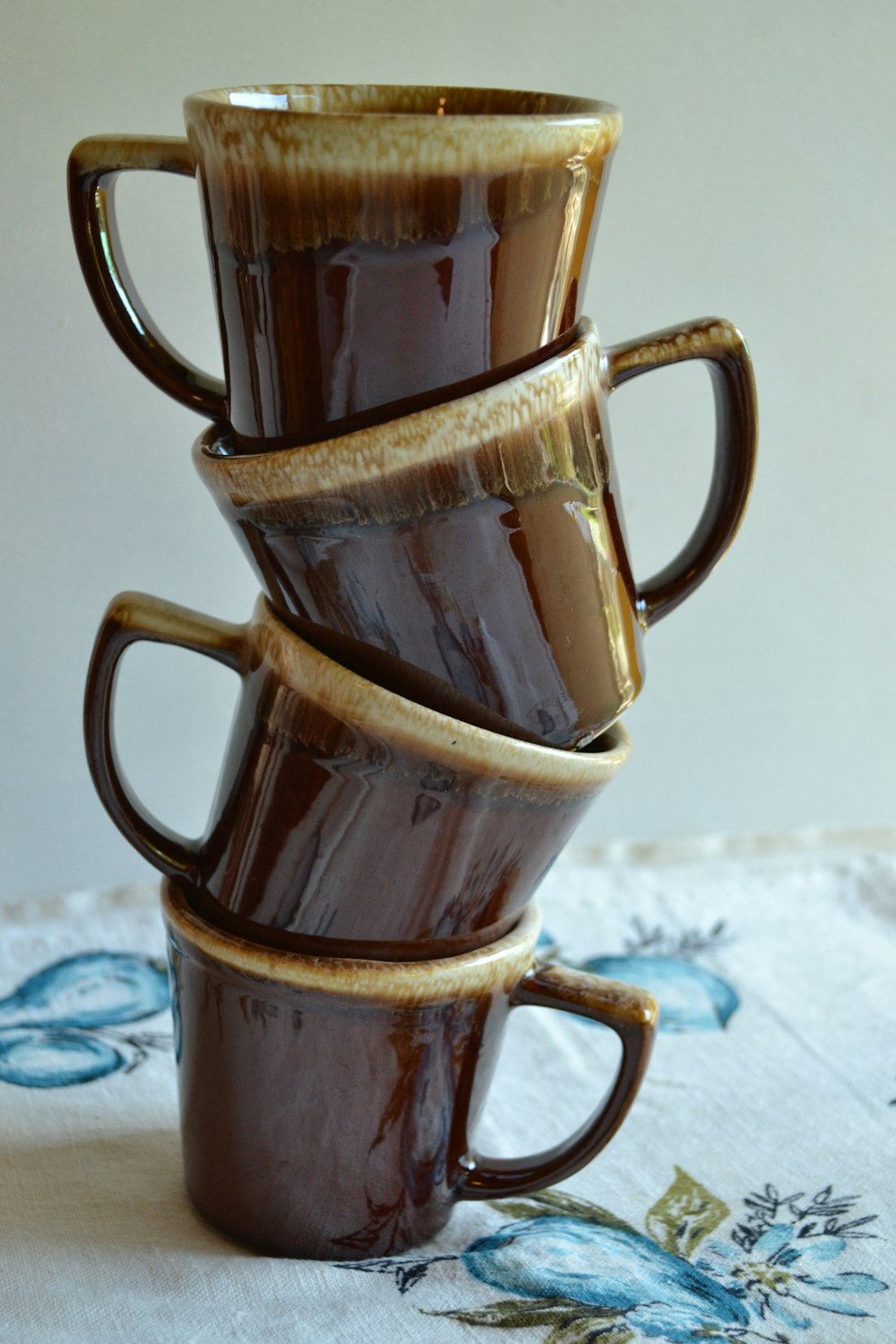 brown ceramic mug on white and blue floral textile