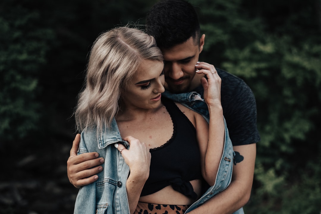 woman in black tank top and blue denim jacket hugging man in blue denim jacket