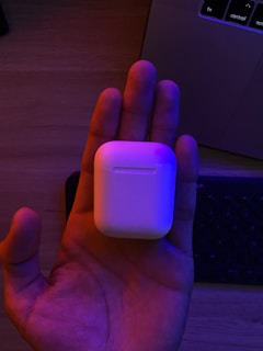 Hands holding a wireless headset in a bright office environment