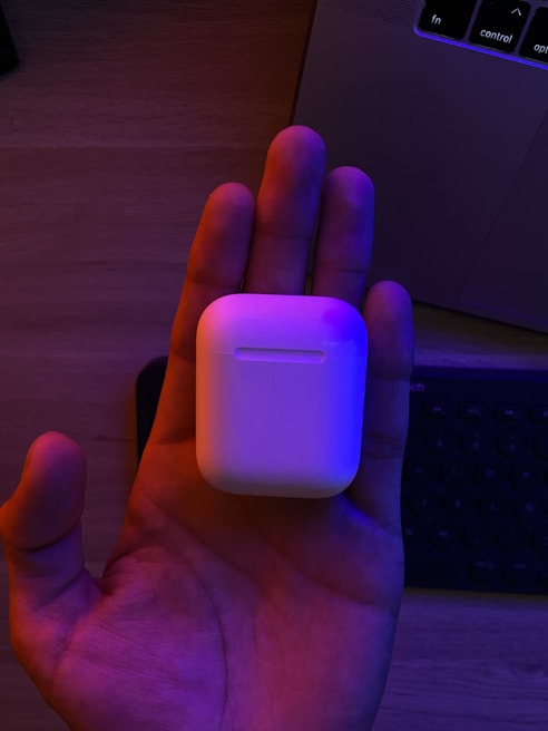 Hands holding a wireless headset in a bright office environment