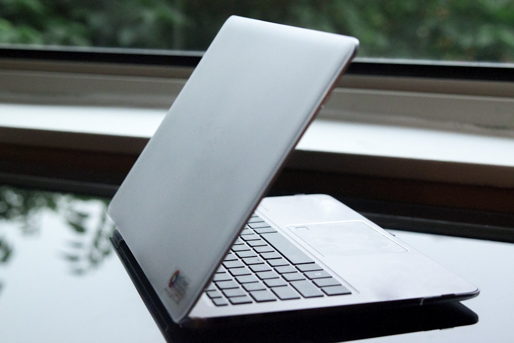 silver laptop computer on white table