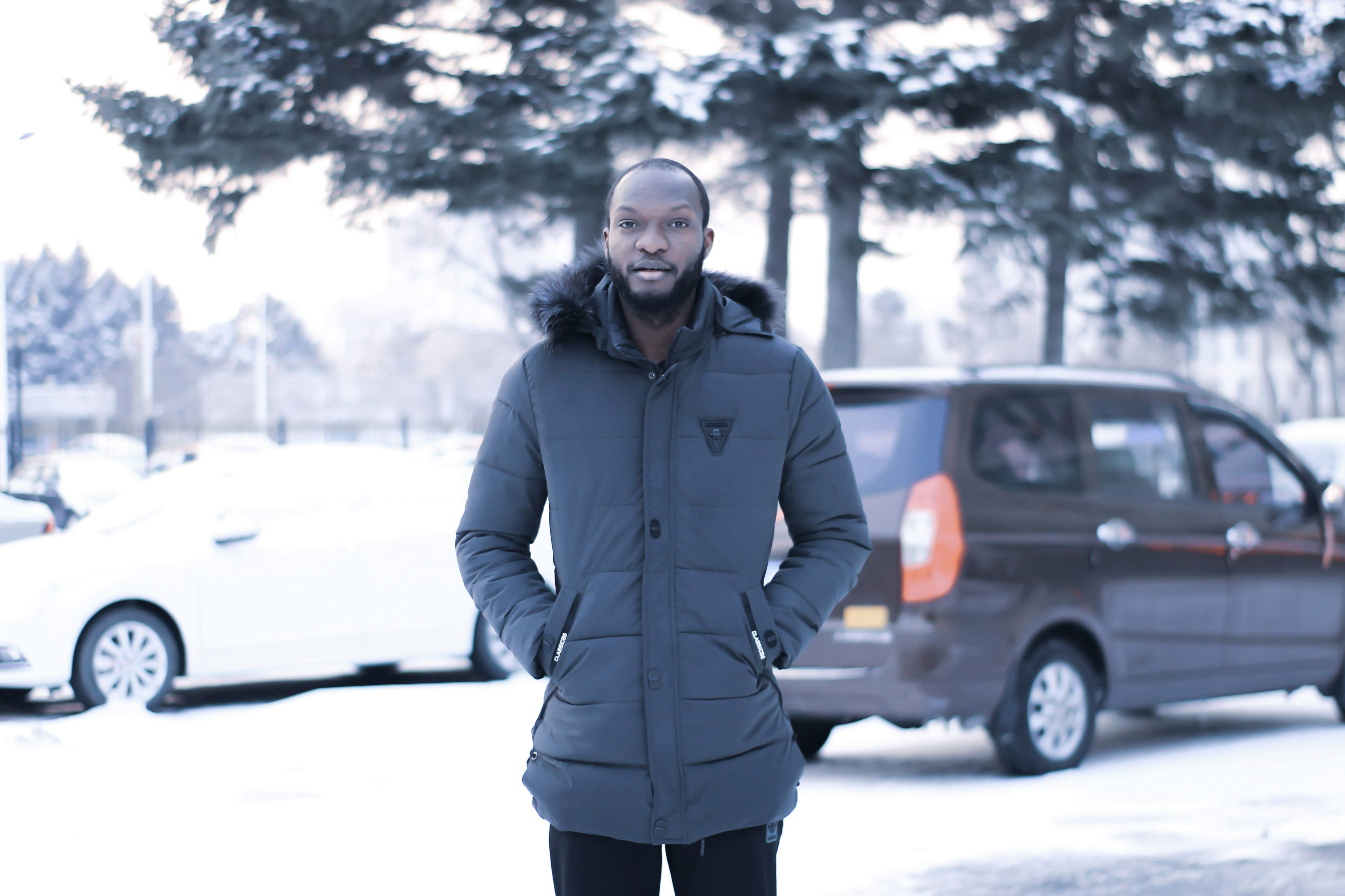 雪に覆われた地面に立つグレーのジップアップジャケットを着た男性