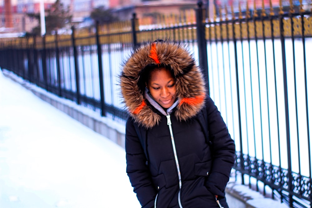 woman in black and brown parka jacket standing on snow covered ground during daytime