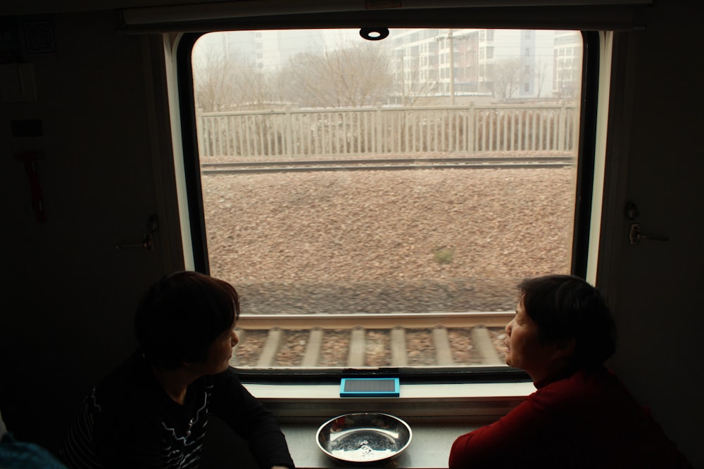 woman in red shirt sitting beside window