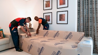 A team carefully removing furniture during a house clearance in a cozy living room.