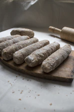 Photo of artisanal precooked pinsa bases stacked on a rustic wooden table in a Roman workshop.
