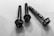Three metal screws are arranged on a flat surface, casting shadows. The screws have helical ridges along their bodies and hexagonal heads, appearing worn with slight rust.