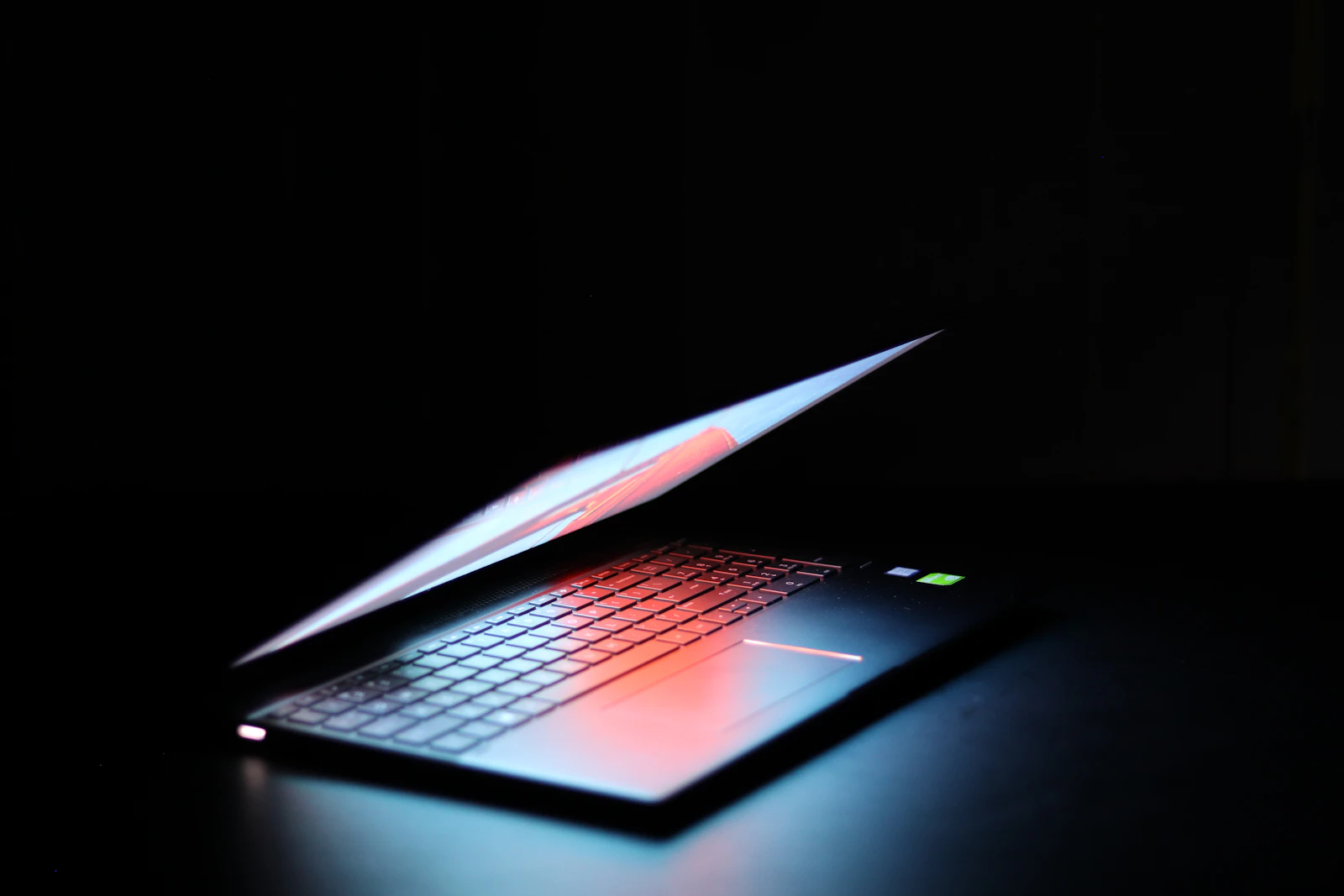 Black and gray laptop computer turned on in dark room
