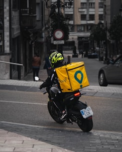 man in yellow helmet riding black motorcycle on road during daytime