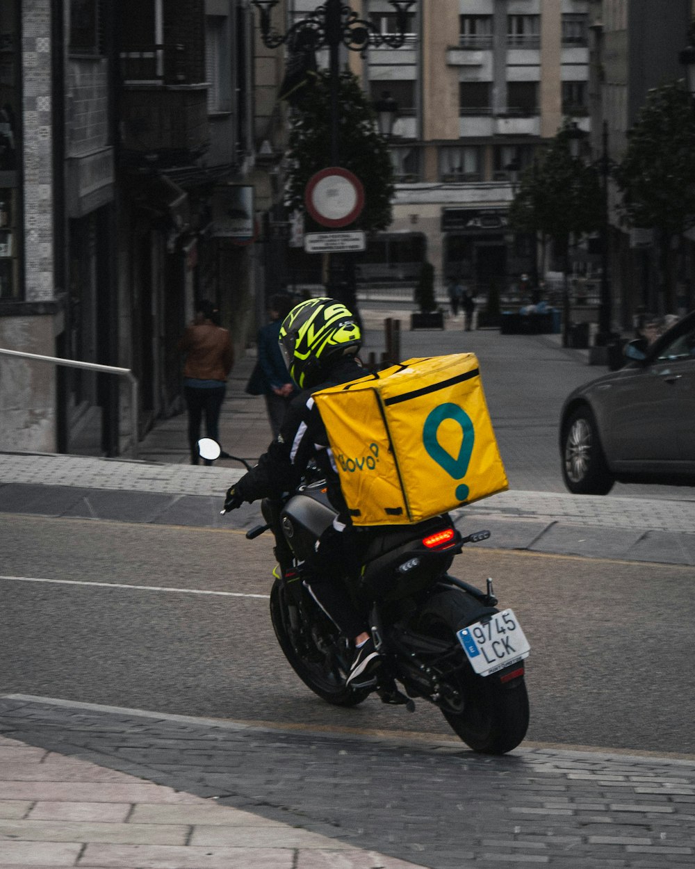 昼間の道路で黒いバイクに乗る黄色いヘルメットの男