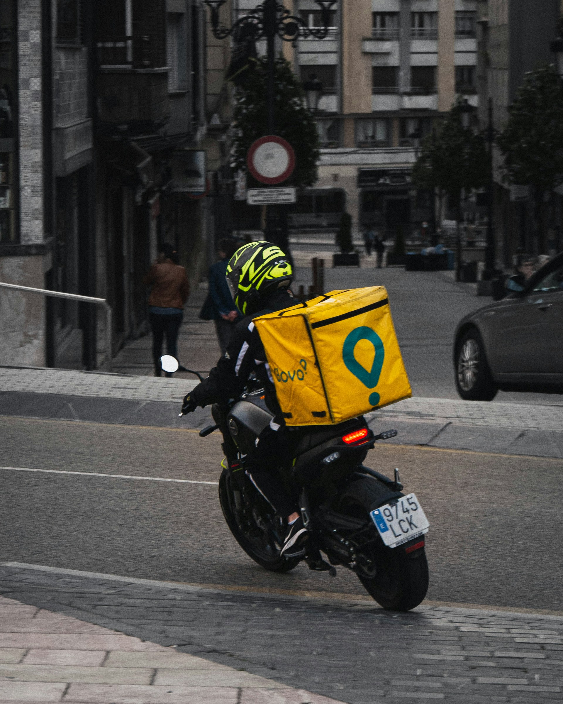 man in yellow helmet riding black motorcycle on road during daytime