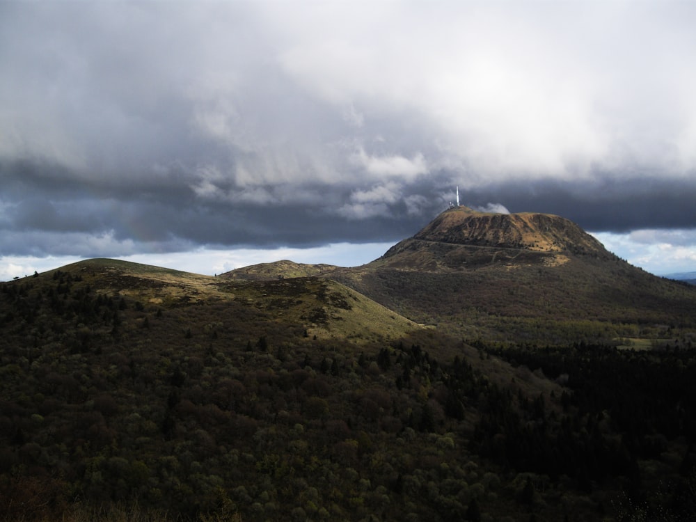 montagne verte et brune sous les nuages blancs pendant la journée