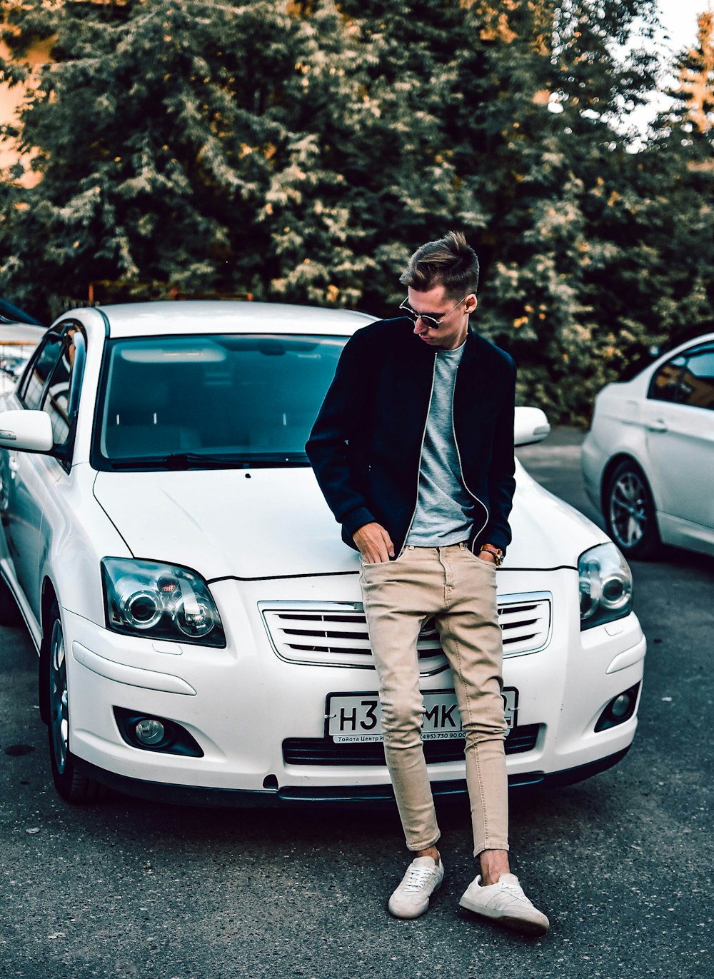 man in black jacket standing beside white mercedes benz car