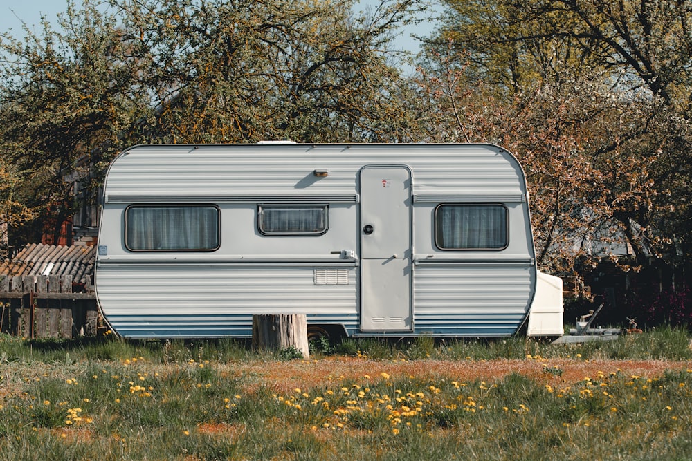 Remolque camper blanco y gris en campo de hierba verde