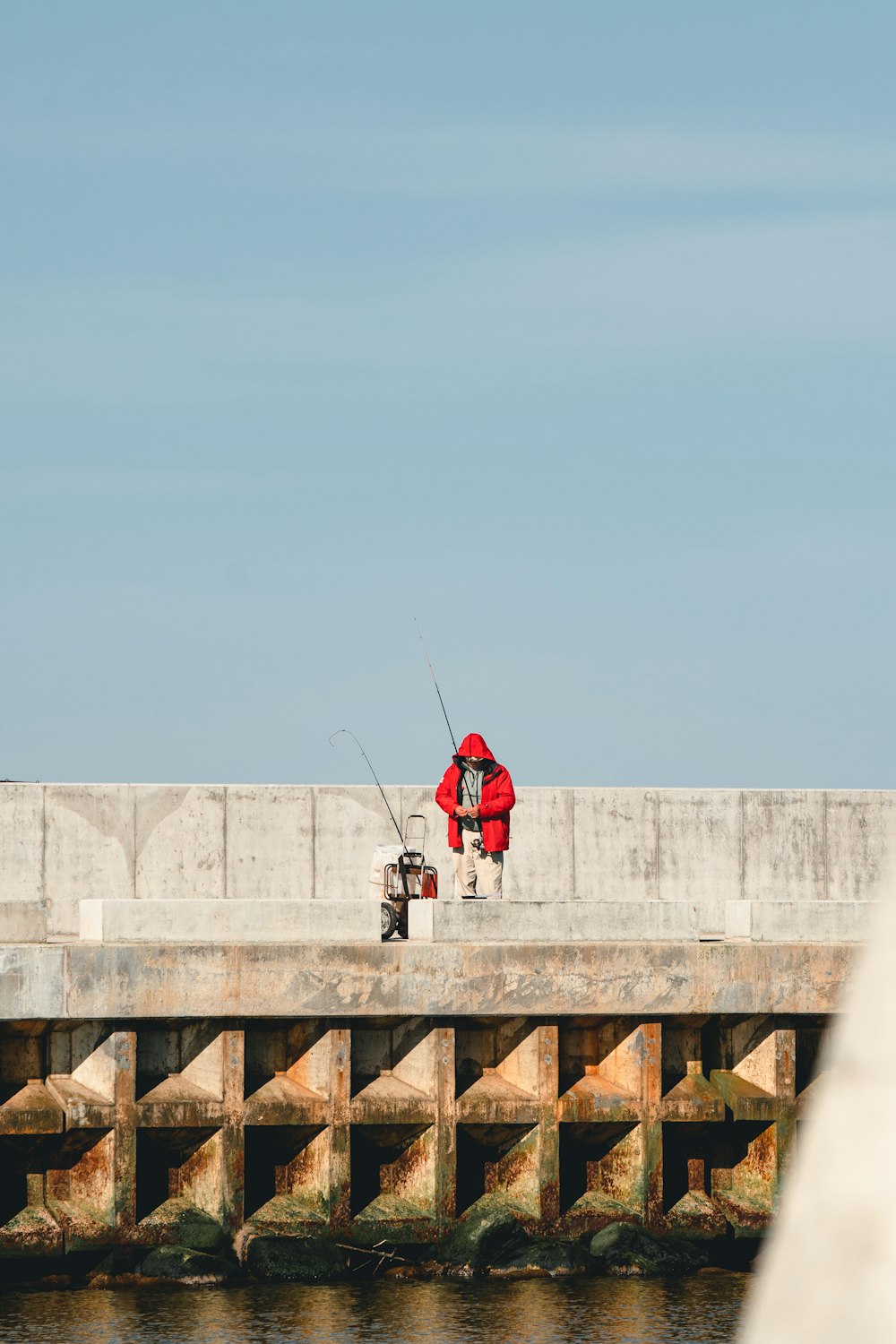 person in red jacket and black pants standing on concrete dock