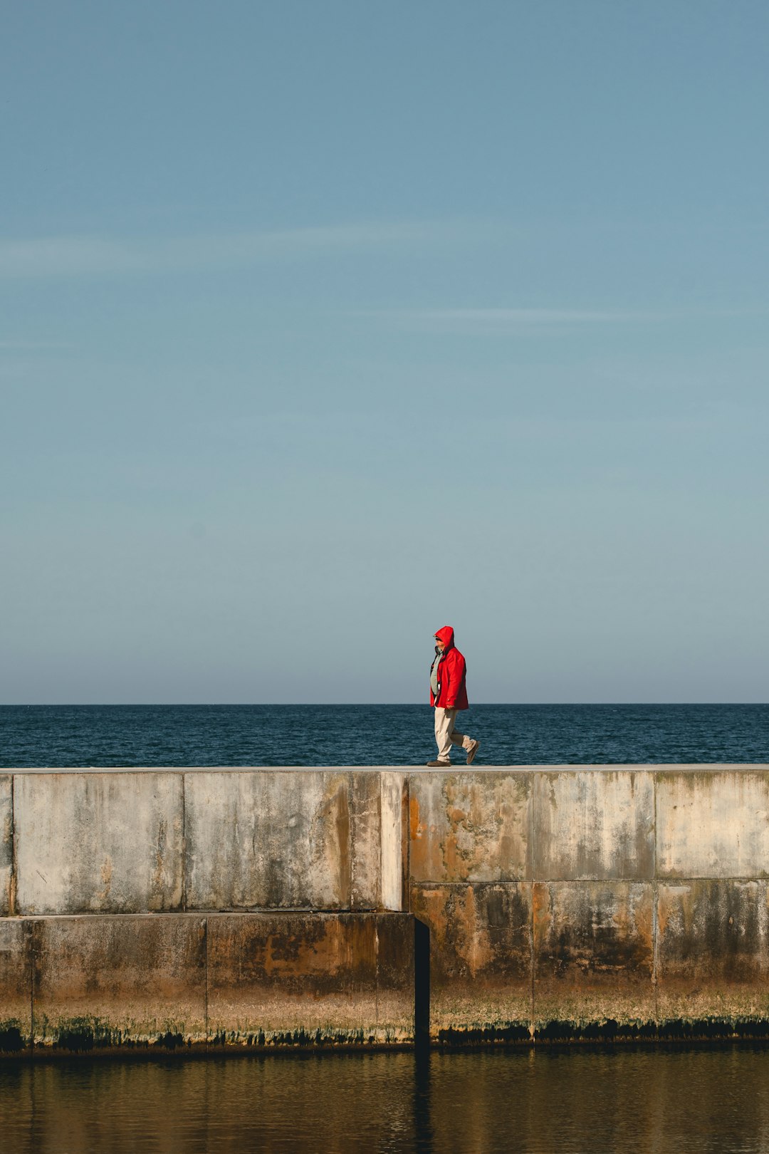 person in red jacket standing on concrete dock during daytime