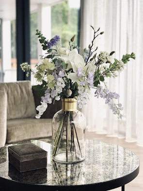 Luxurious floral arrangement with white lilies and greenery on a marble table.