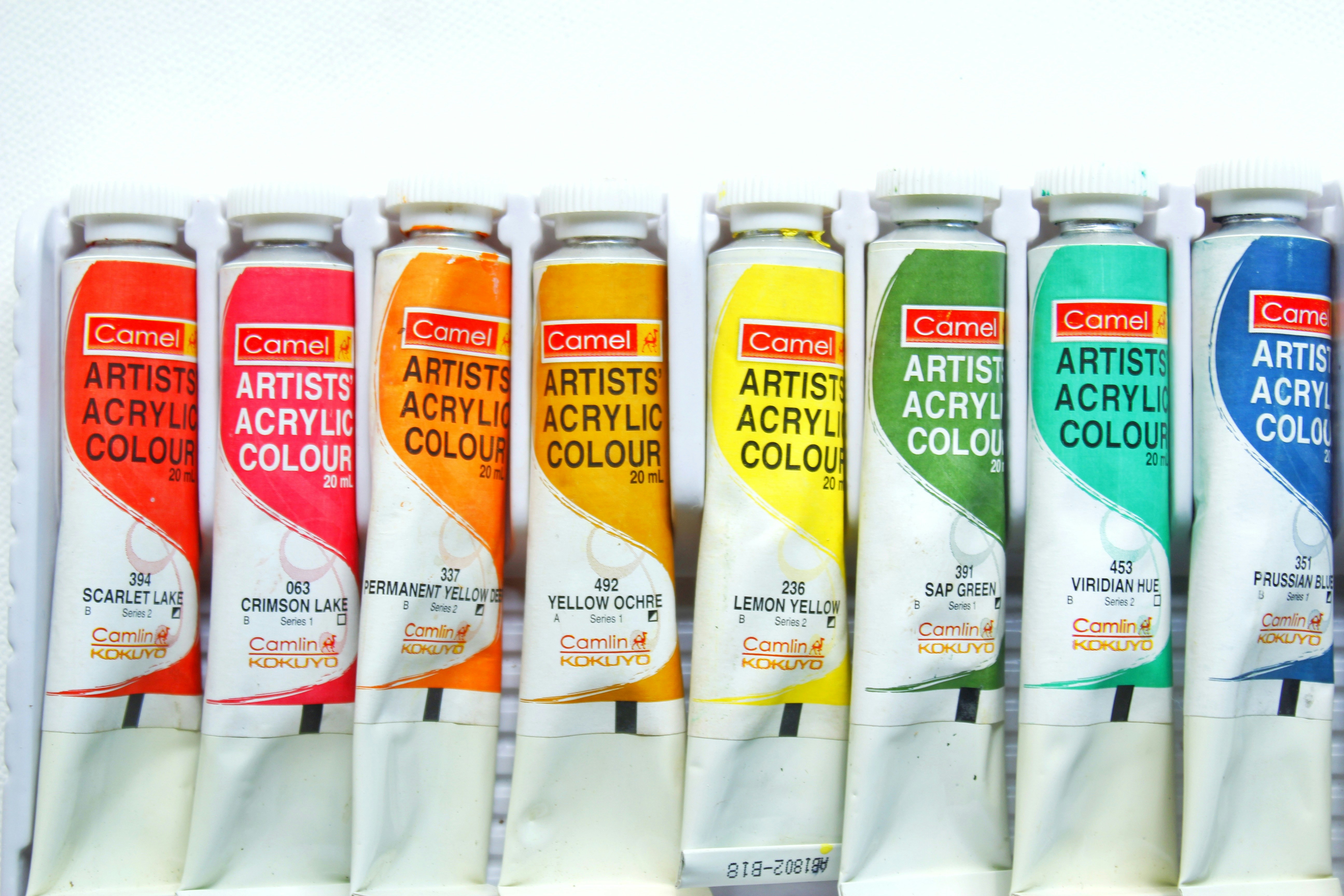 Tubes of acrylic paint arranged on an artist's table.