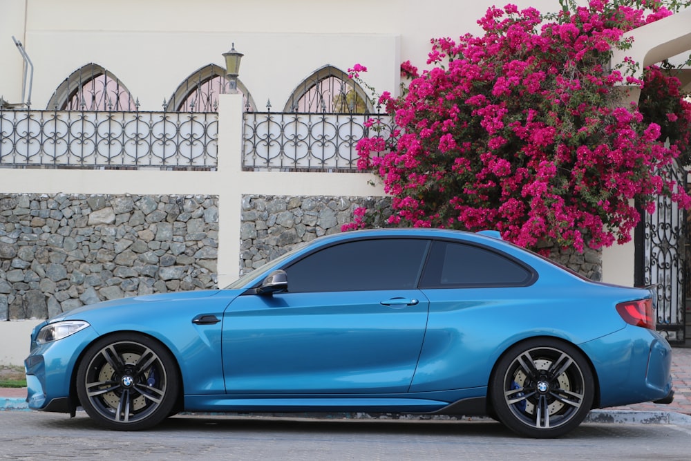 blue coupe parked beside white fence