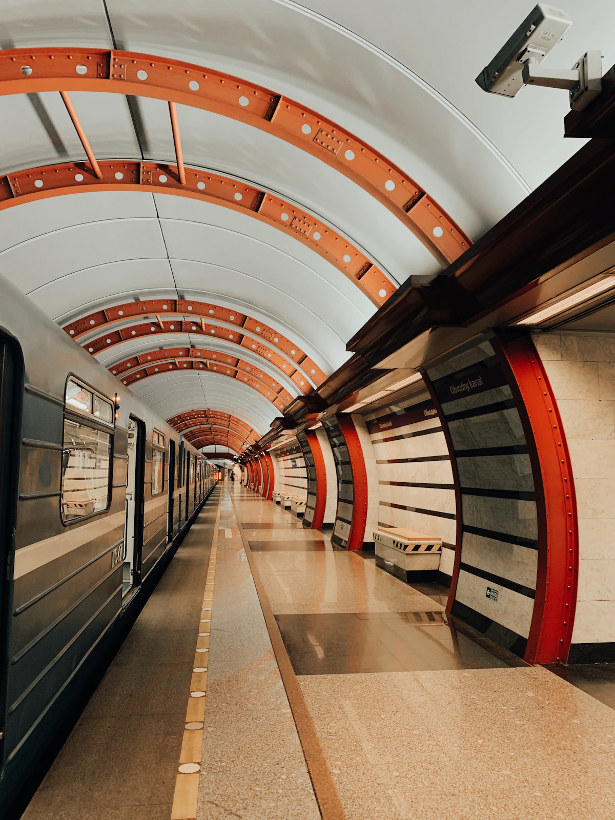 An underground railway station platform with tiled walls and a train waiting at the edge