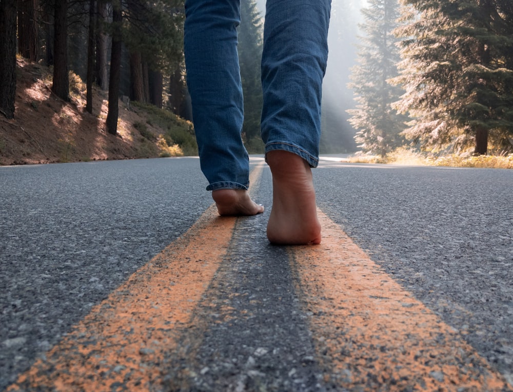 person in blue denim jeans standing on gray concrete road during daytime