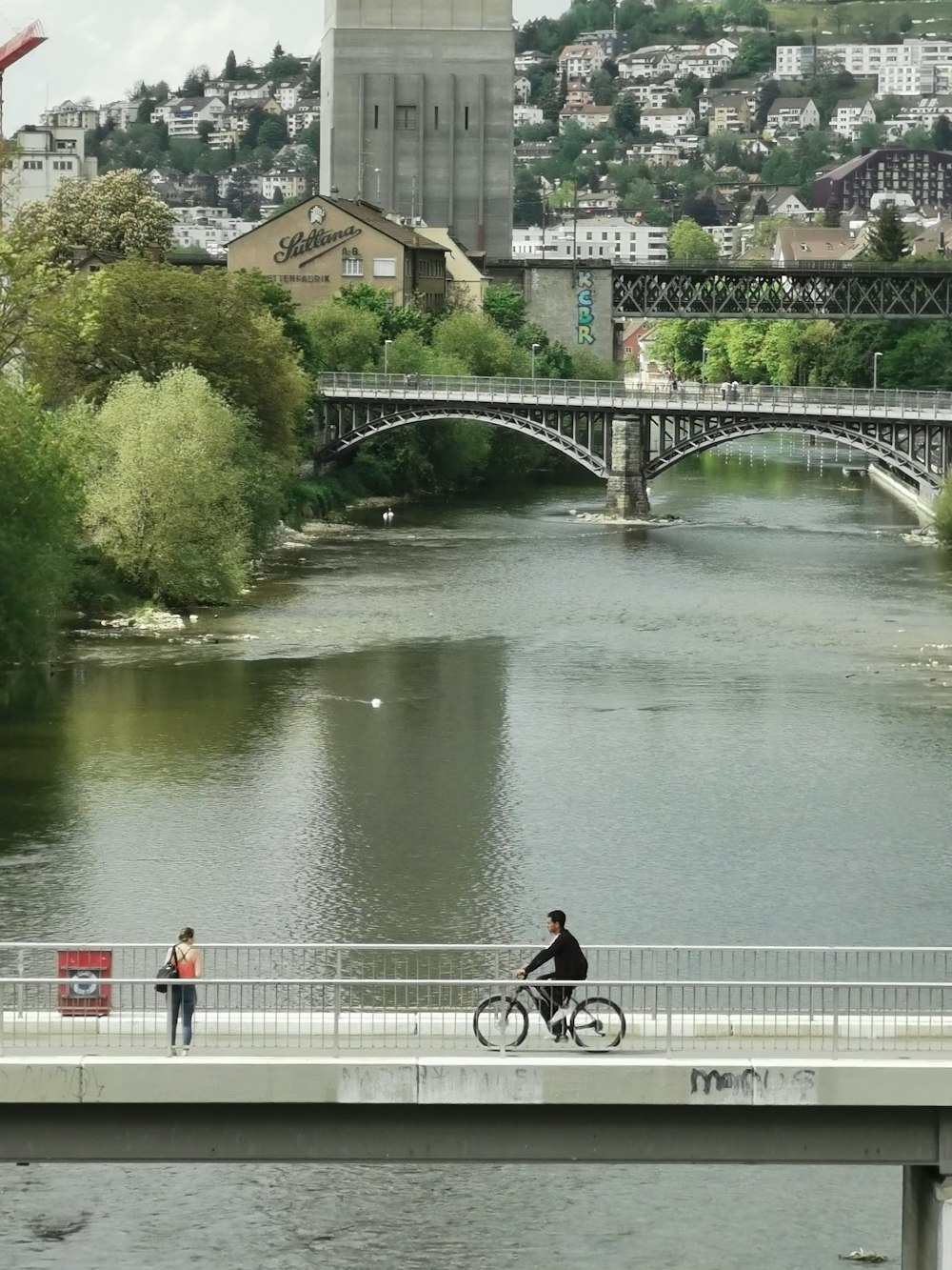 a man riding a bike across a bridge over a river