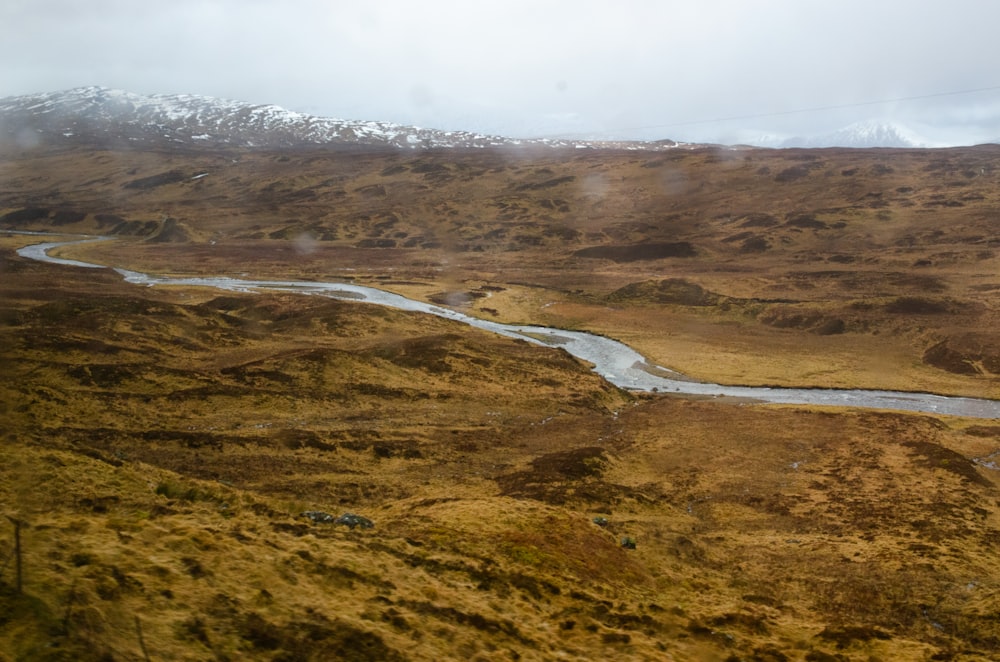 aerial view of road in the middle of green and brown grass field