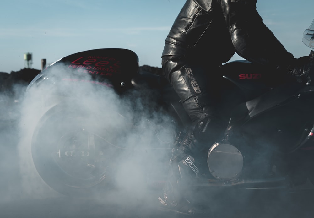 person in black leather jacket and red helmet riding black motorcycle