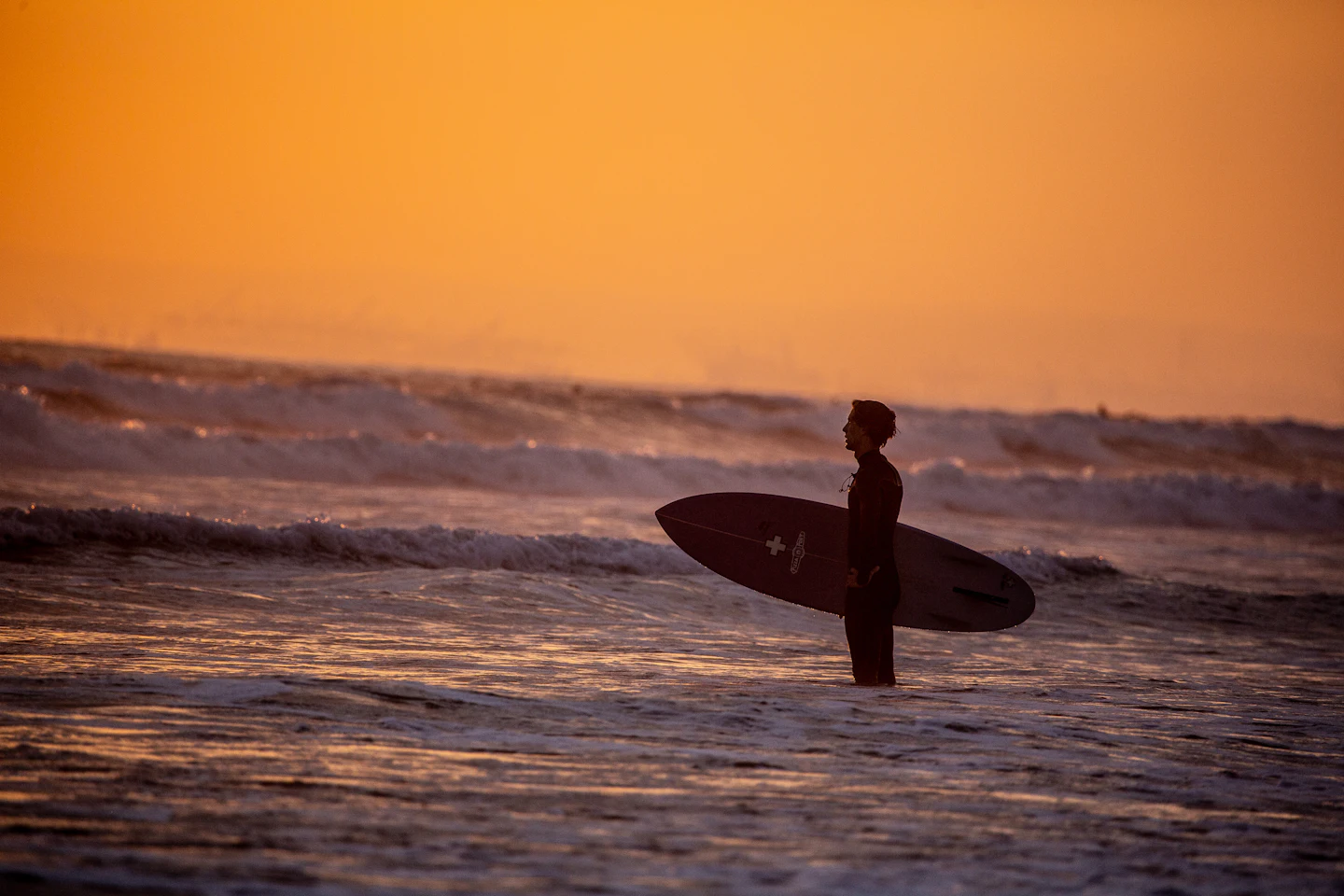 A surfer with a board at dusk