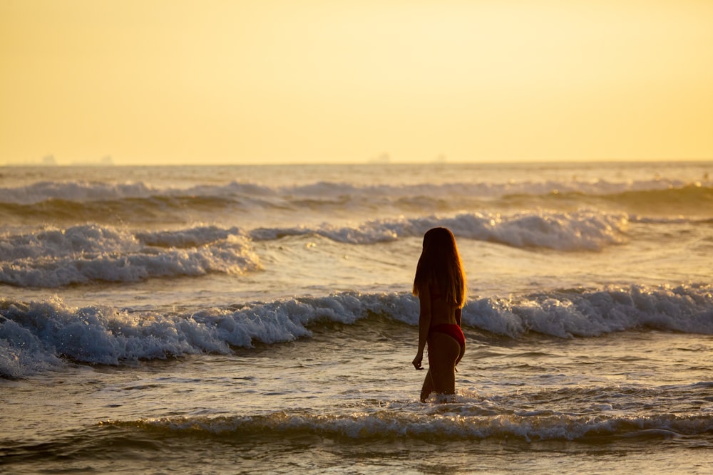 woman in black dress standing on beach during daytime