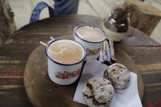 A steaming cup of rich coffee poured into a simple ceramic mug, beside a stack of soft, chewy cookies dusted with powdered sugar.
