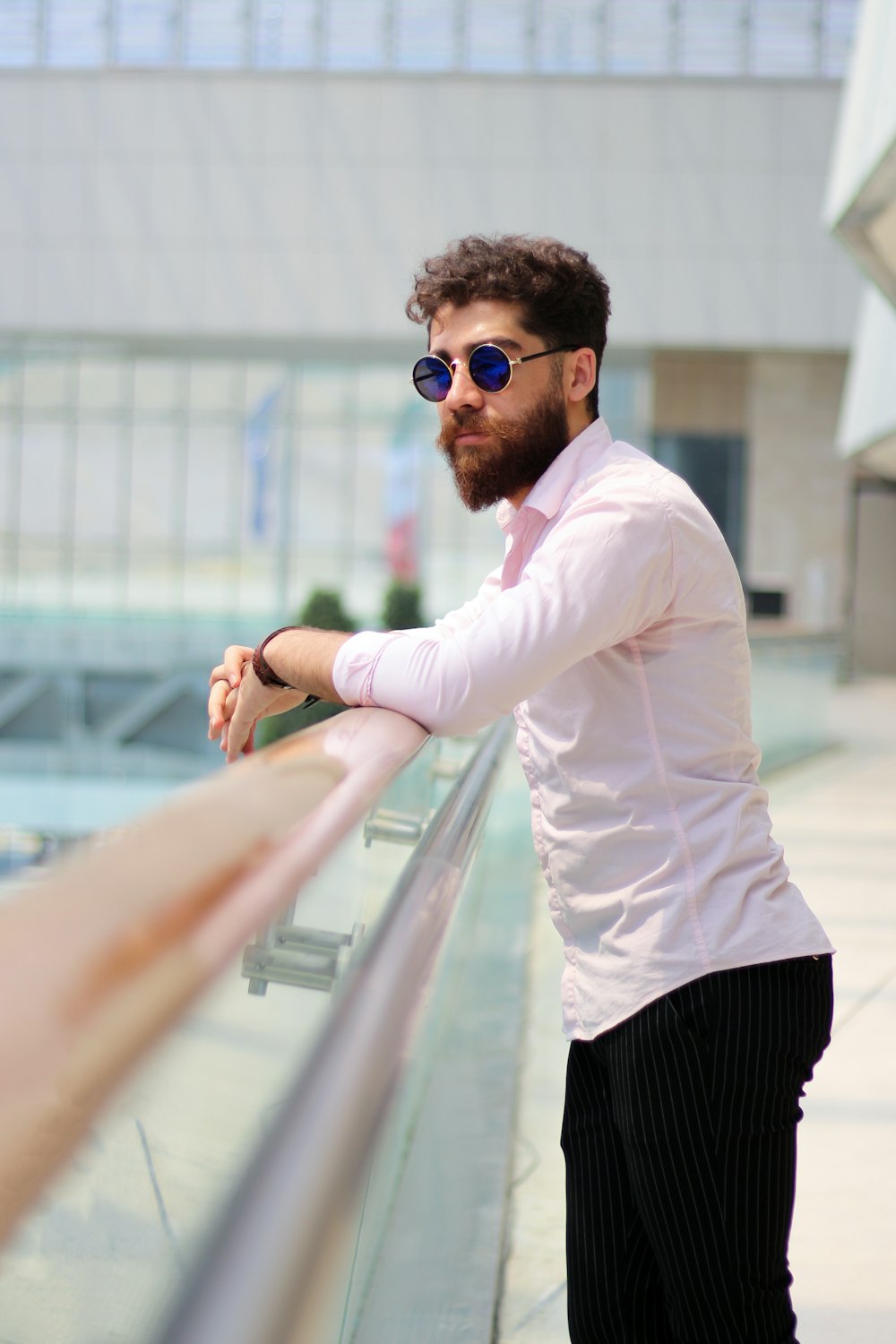 Hombre con camisa de vestir blanca y pantalones negros con gafas de sol negras de pie en la escalera mecánica