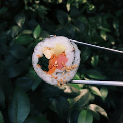 A vibrant sushi roll being prepared with fresh ingredients in a lively Barcelona street setting.