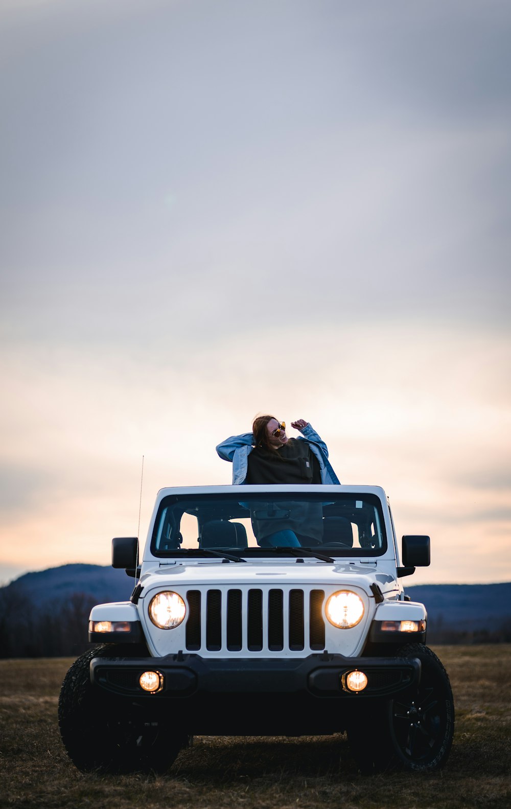 man and woman kissing on top of jeep wrangler