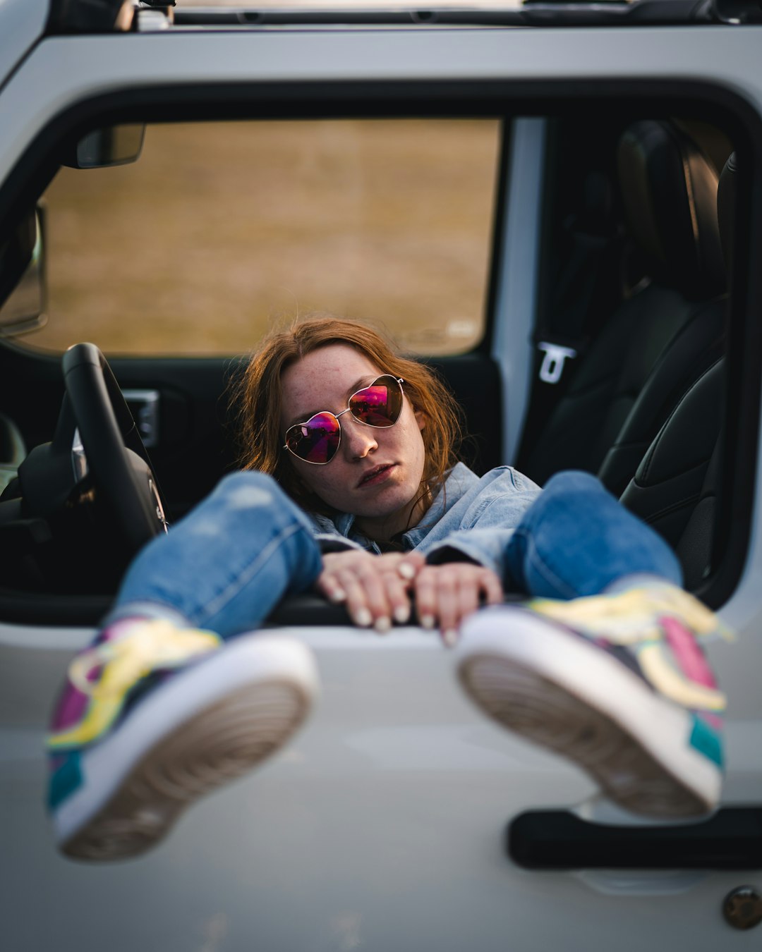 girl in blue denim jeans wearing white and purple nike sneakers sitting on car seat