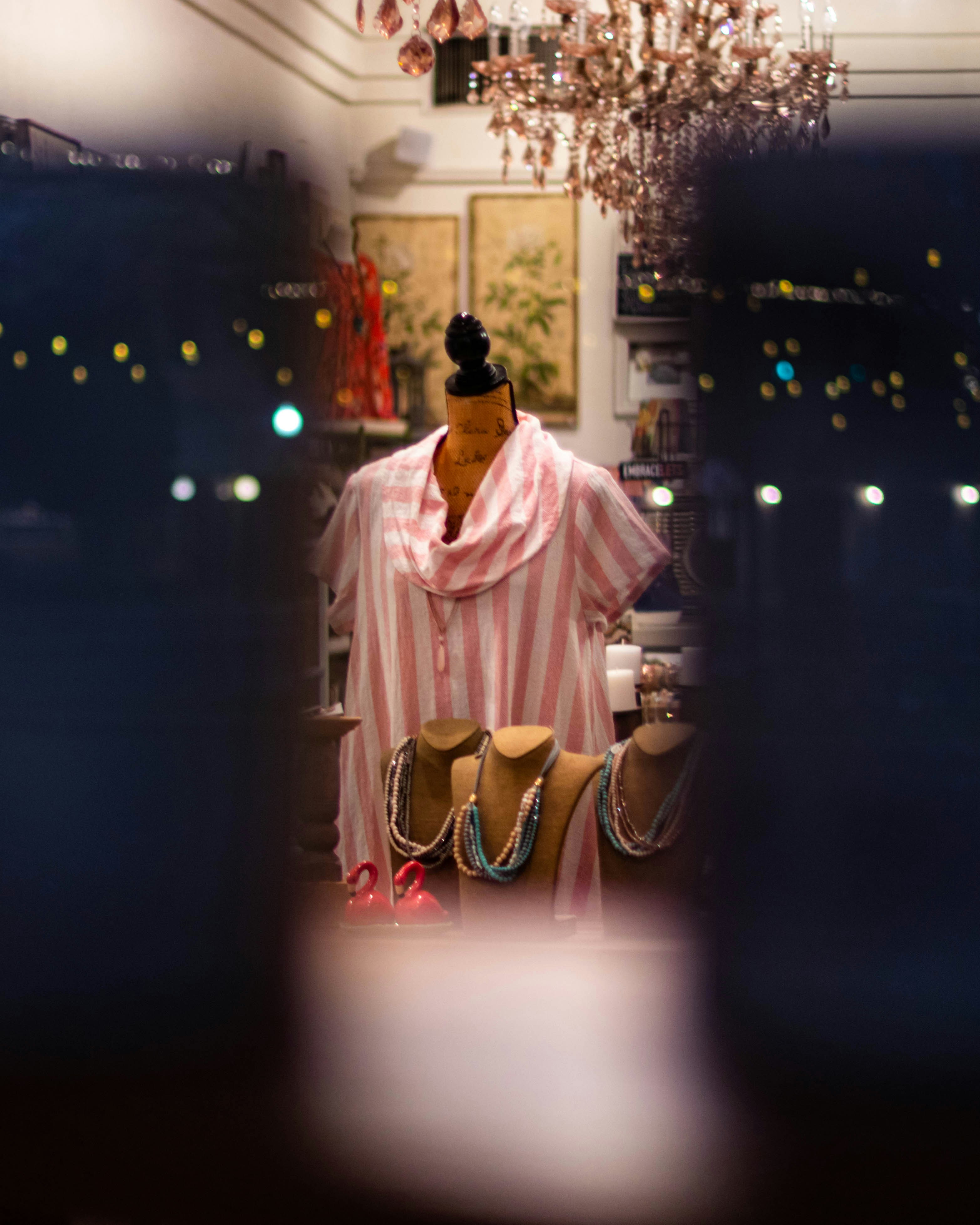 ピンクのドレスと黒い帽子をかぶった女性が夜、白い建物の前に立つ