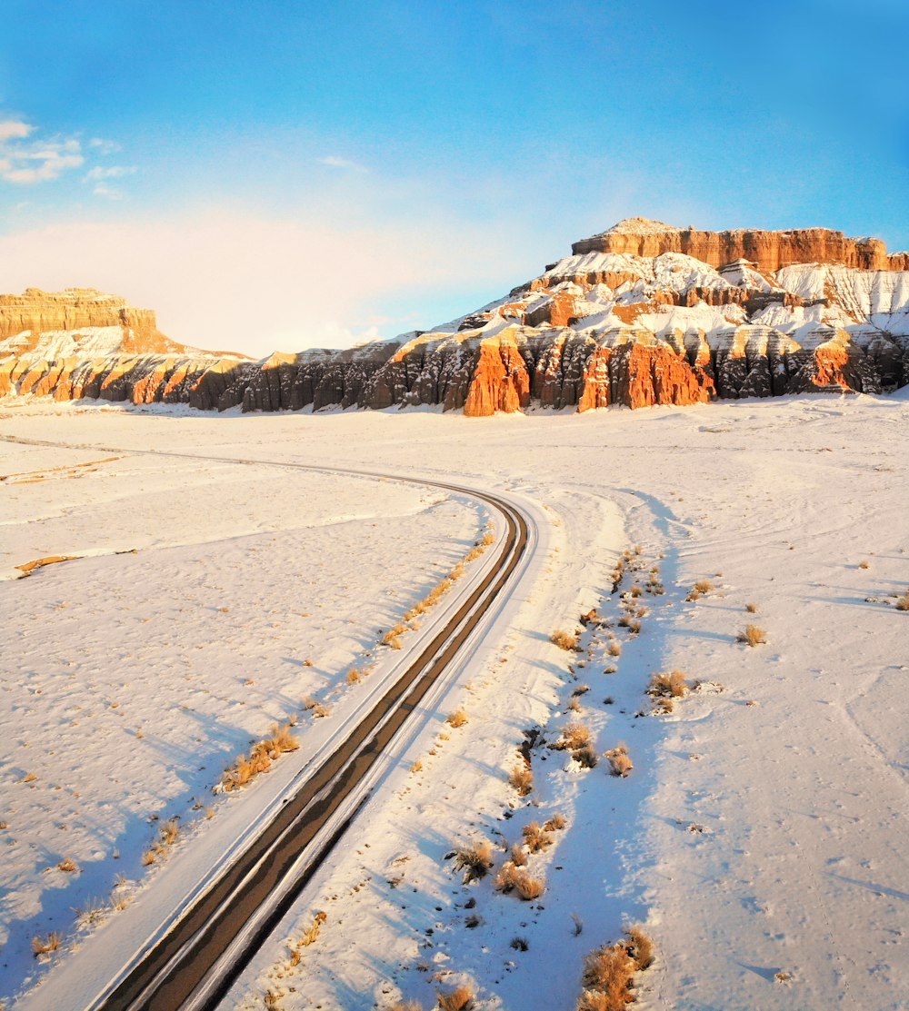 snow covered road near brown mountain during daytime