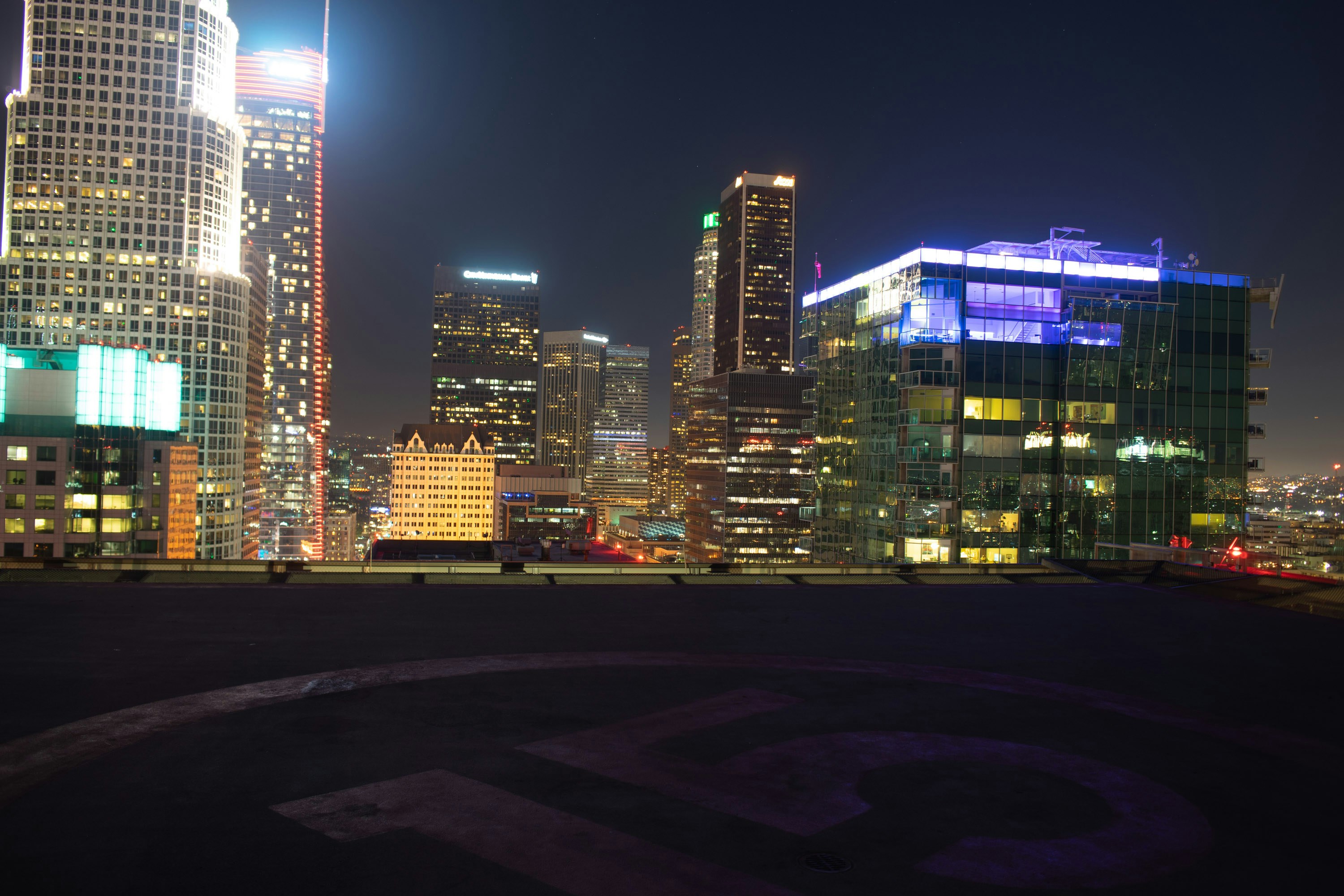 Modern helicopter on helipad at night, city lights in background, dark atmospheric scene, blue accent lighting