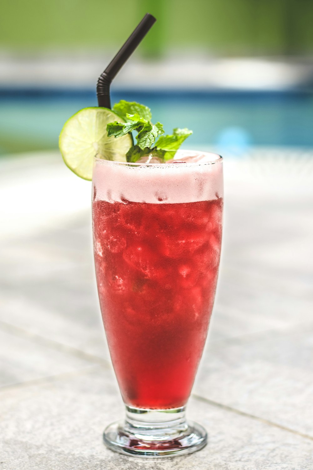 clear drinking glass with red liquid and black straw