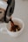 Hands pouring freshly brewed coffee from a French press into a ceramic cup.