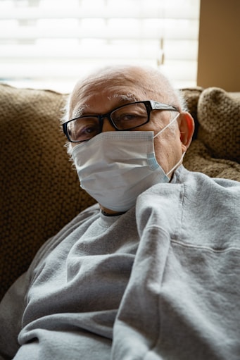 man in gray sweater wearing white mask