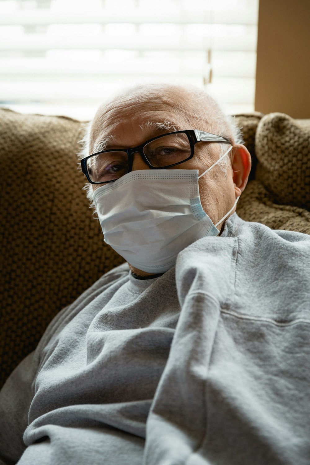 man in gray sweater wearing white mask