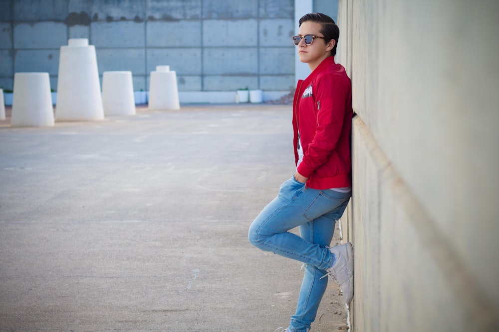 Foto Hombre con camisa roja de manga larga y jeans azules sentado en un de concreto blanco durante – Imagen Vestir gratis en Unsplash