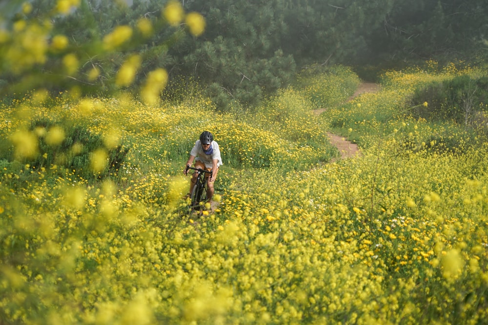 man in white t-shirt and black shorts walking on yellow flower field during daytime